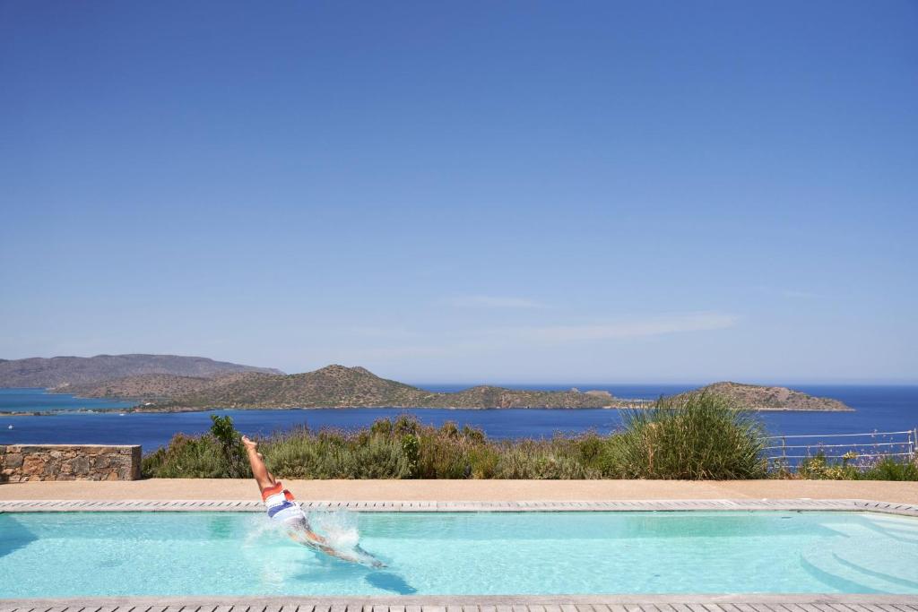 a woman is swimming in a swimming pool at Elounda White Pearl Villa in Agios Nikolaos