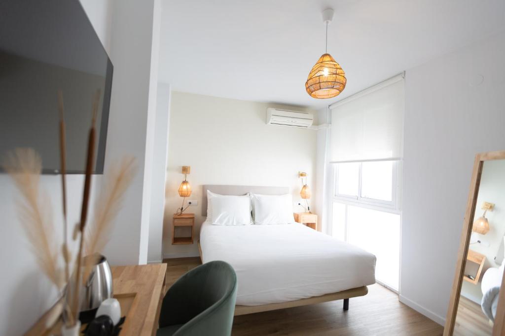 a white bedroom with a bed and a window at Hostal Boutique La Malagueña - Only Adults in Estepona