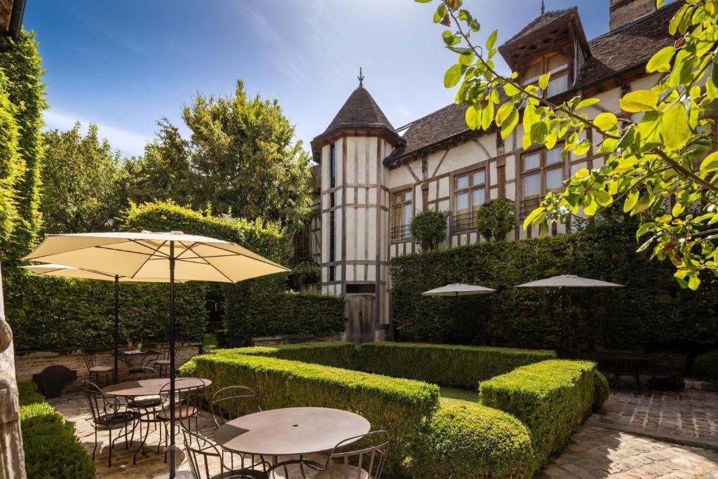 Hôtel la Maison de Rhodes & Spa في تروي: ساحة فيها طاولات ومظلات امام المبنى