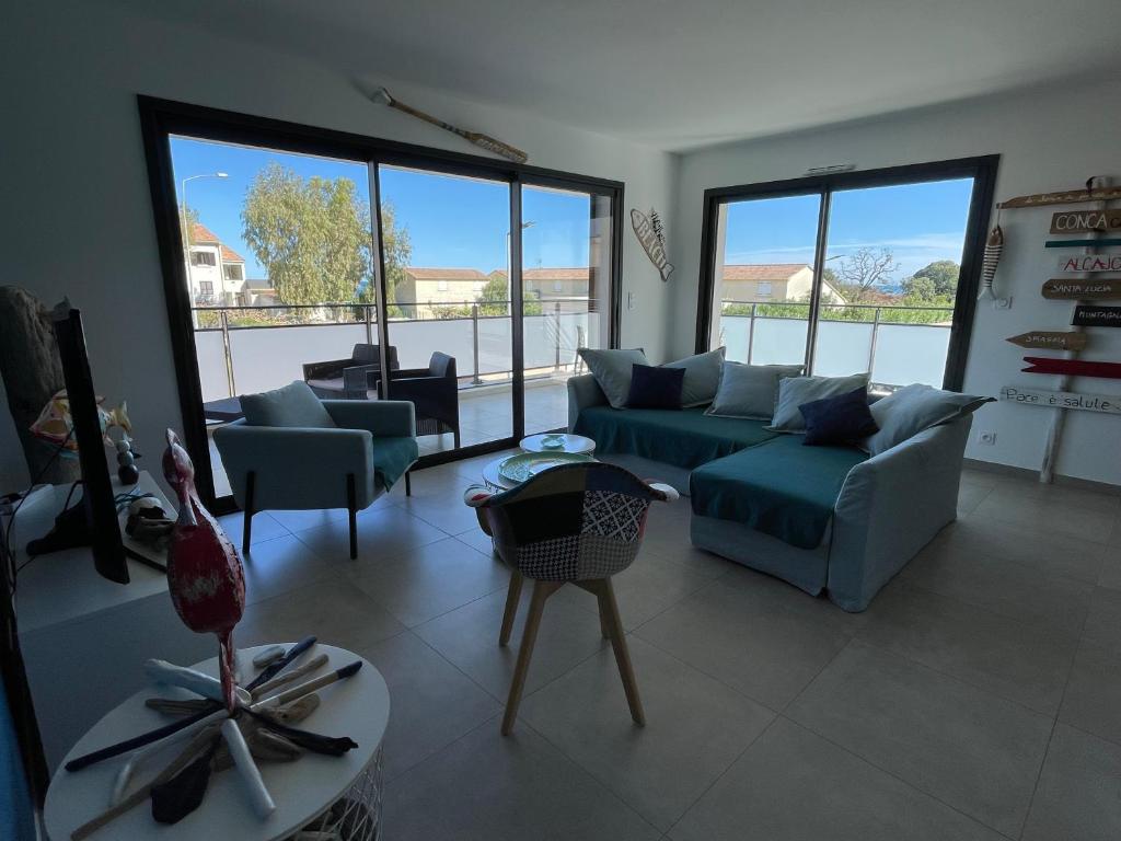 a living room with a couch and chairs and windows at Les Toits de Moriani in San-Nicolao