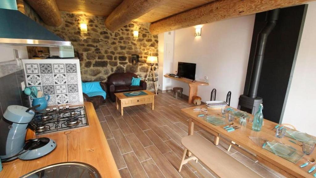 Il comprend une cuisine et un salon avec une table et une cuisinière. dans l'établissement Gite Le Turquoise, à Saint-Cirgues-en-Montagne