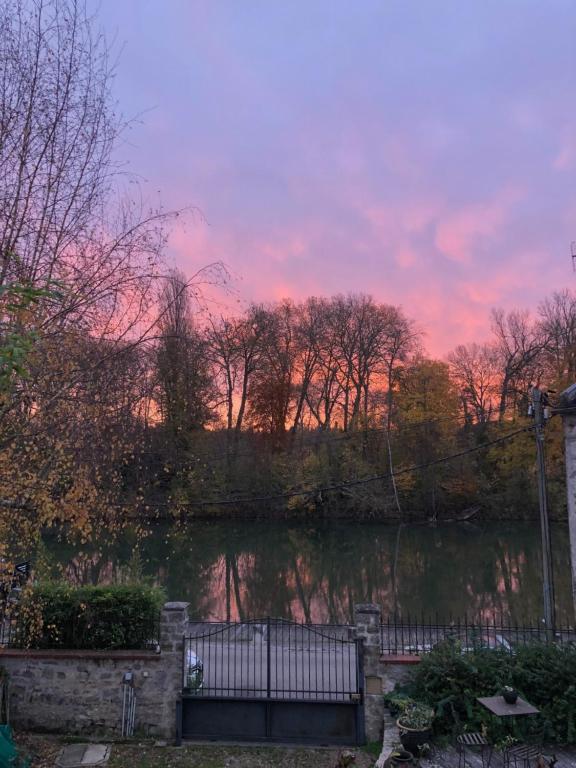 un coucher de soleil sur un étang avec une clôture et des arbres dans l'établissement la Belle Seine, à Samois-sur-Seine