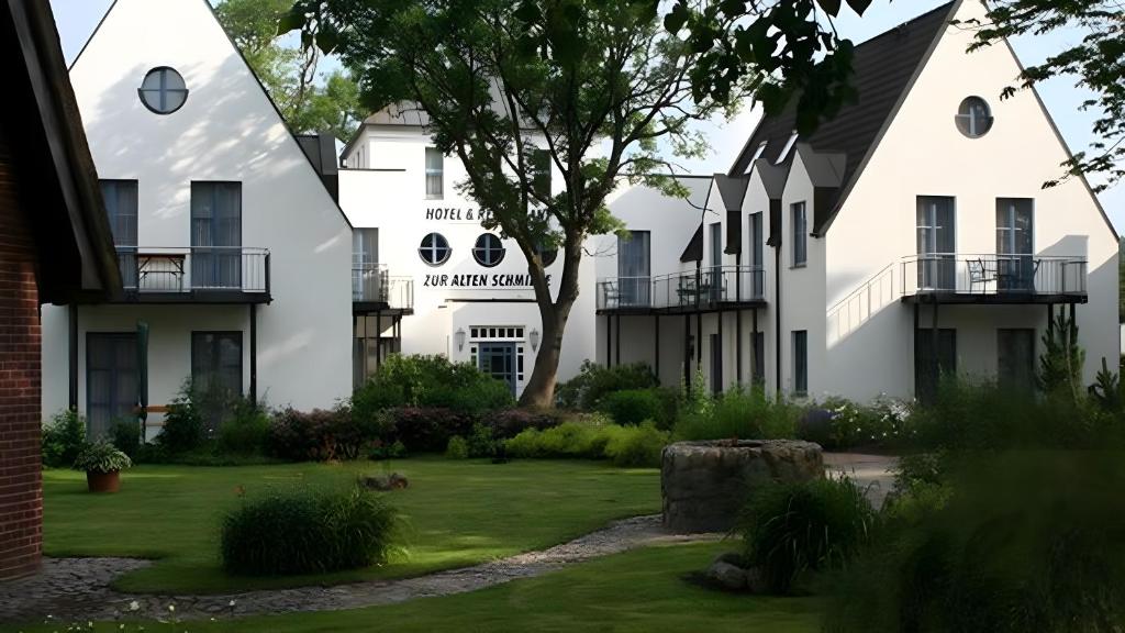 a row of white buildings with a green yard at Hotel Zur alten Schmiede in Schaprode