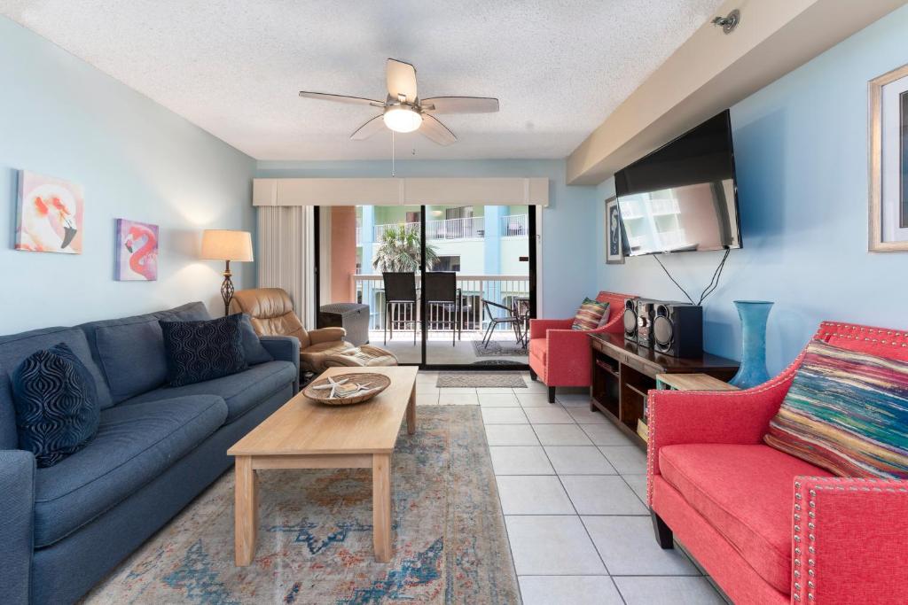 uma sala de estar com um sofá azul e cadeiras vermelhas em Harbour Place Unit 106 em Orange Beach