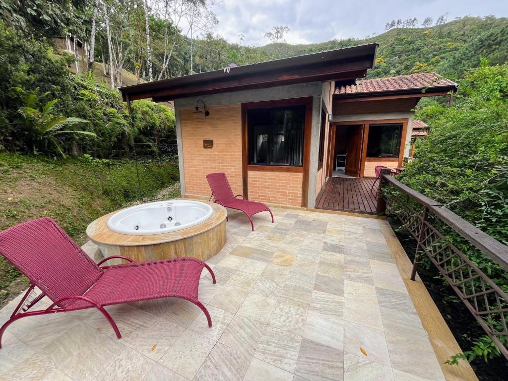 un patio con sillas, una mesa y una casa en Hospedaria Vila Serra da Luz, en Pindamonhangaba