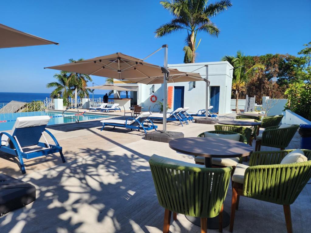 a patio with chairs and tables and an umbrella at Hotel 39 Jamaica in Montego Bay