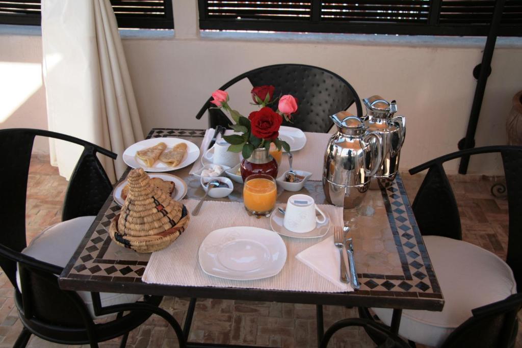 una mesa con alimentos para el desayuno y flores en ella en Riad Diana, en Marrakech