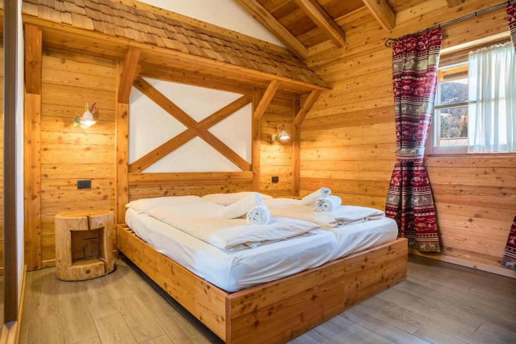 una camera con un letto in una baita di tronchi di Chalet Camping Faè 1 a Madonna di Campiglio