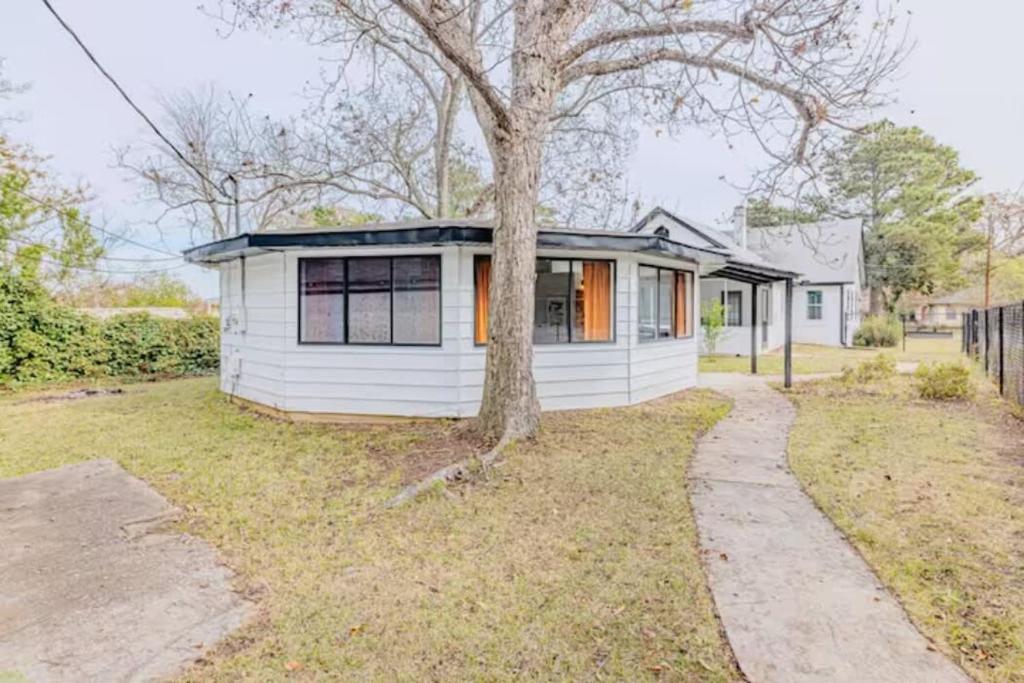 una pequeña casa blanca con un árbol en el patio en Groovy Getaway Centrally Located en Augusta