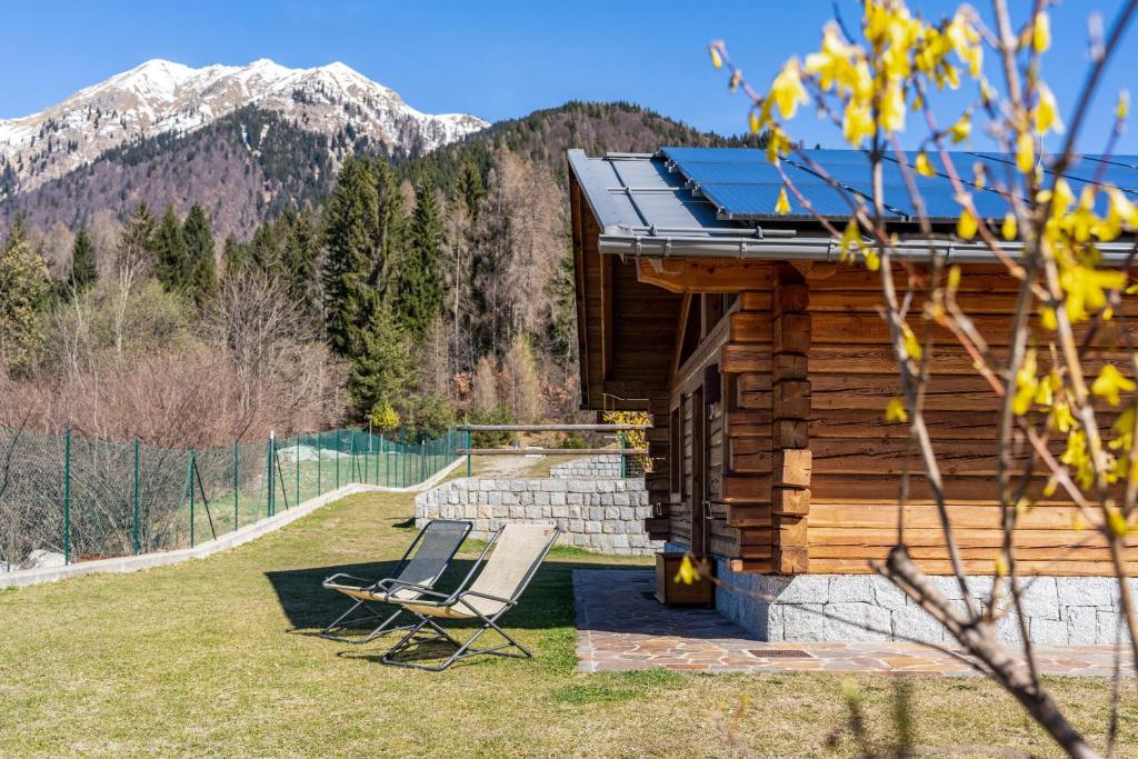 a couple of chairs sitting on the porch of a log cabin at Chalet Camping Faè 3 in Madonna di Campiglio