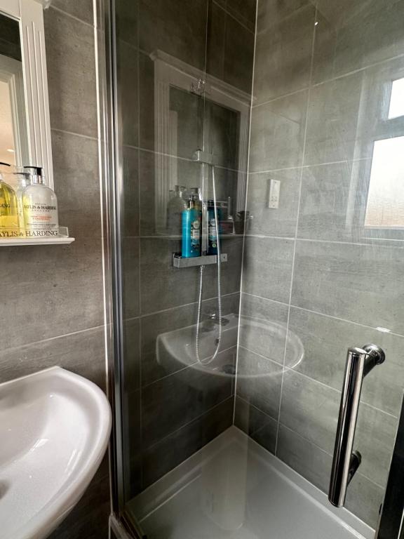 a shower with a glass door next to a sink at Wonderful Double Room In House in London