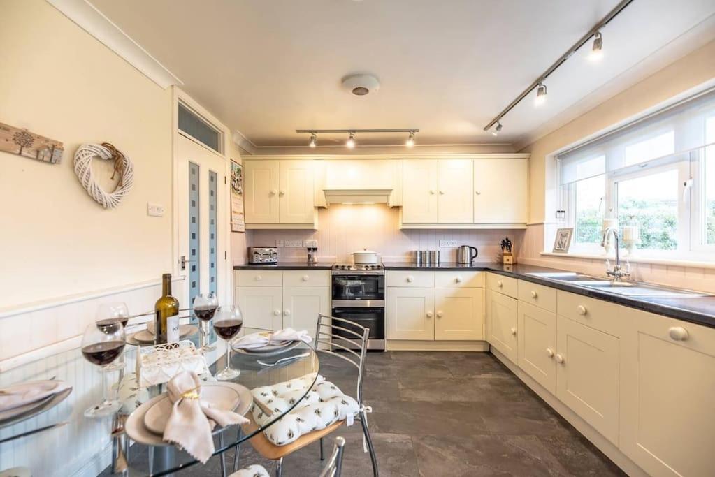 a kitchen with white cabinets and a glass table at 4 The Sandlings in Aldeburgh