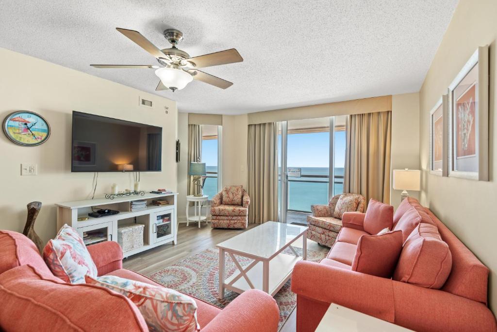 a living room with two red chairs and a flat screen tv at Bahama Sands PH3 - Oceanfront - Crescent Beach Section in Myrtle Beach