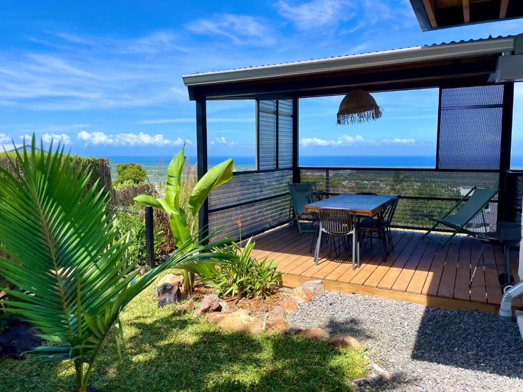 une terrasse en bois avec une table et une vue sur l'océan dans l'établissement Vacoa - Villa Salba. Panoramic view., à L'Étang-Salé