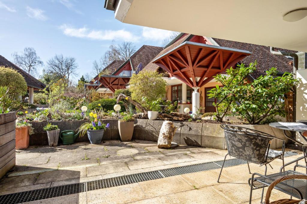 a patio with chairs and plants in front of a house at Claudis Seeland in Kressbronn am Bodensee
