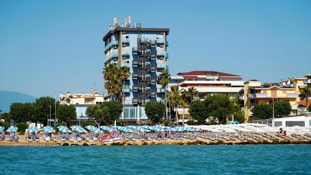 una spiaggia con sedie, ombrelloni e persone di Hotel King ad Alba Adriatica
