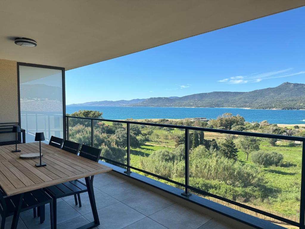 uma varanda com uma mesa de madeira e vista para a água em Appartement tout confort vue mer em Propriano