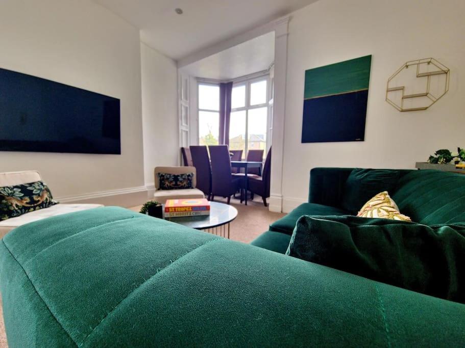 a living room with a green couch and a table at The Stray adjacent, Interior-Designed 2-bed Apartment- Luxury in Harrogate