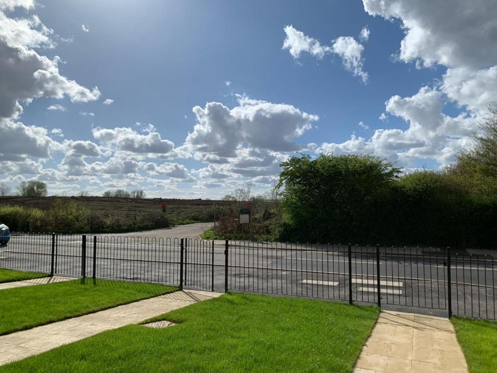 a fence in front of a field with a road at Brand New Entire 4 Bed House Multiple Free Parking Early Check-in Late Check- Out Allowed in South Ockendon