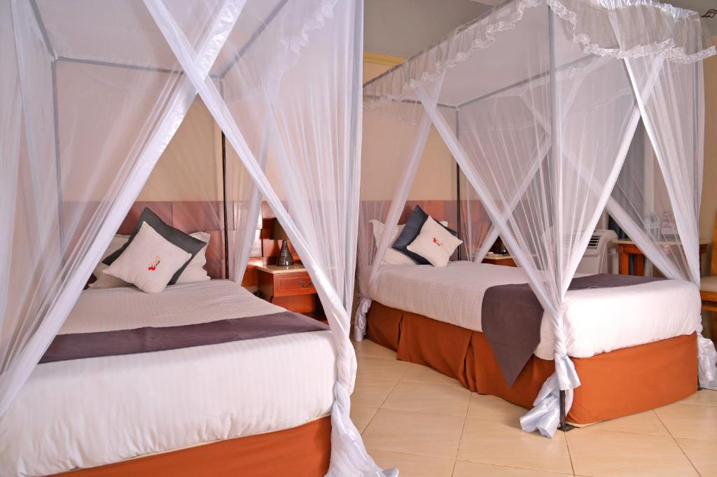 two beds in a room with mosquito nets at ESCAPE VILLAGE HOTEL in Yumbe