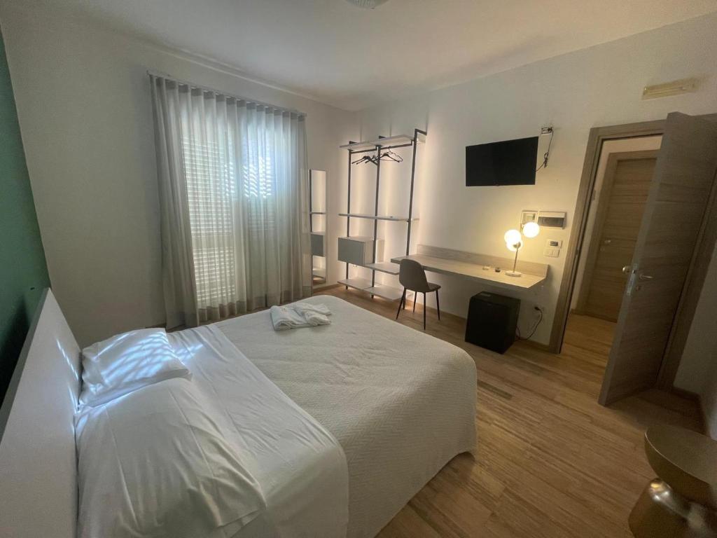 a bedroom with a white bed and a desk at Albergo Perseo in Portopalo