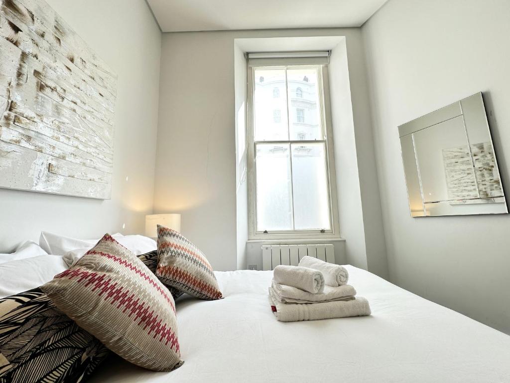 - une chambre avec un lit blanc et des serviettes dans l'établissement Chic apartment in Queensway for six guests, à Londres