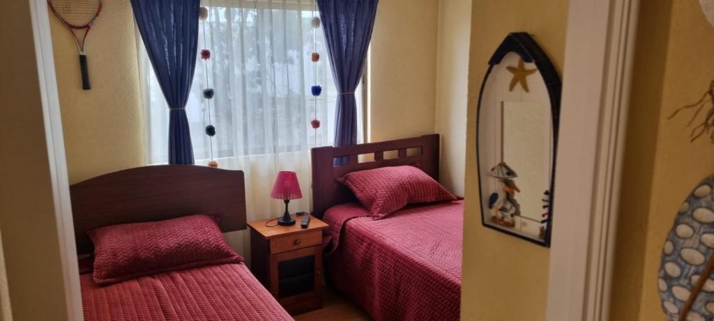 a small bedroom with two beds and a mirror at Casa Condominio Papudo Punta Puyai 3 dormitorios in Papudo