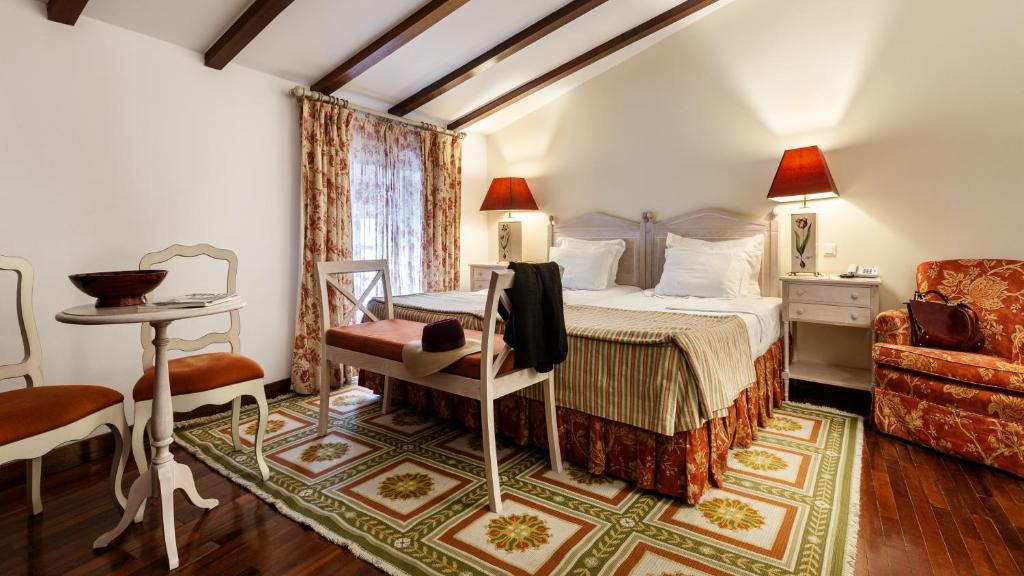 a bedroom with a bed and a desk and a chair at Pousada de Marvao in Marvão