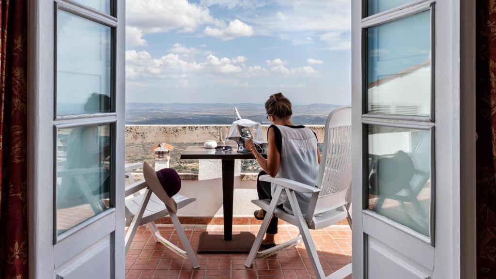 a woman sitting at a table with a laptop on a balcony at Pousada de Marvao in Marvão
