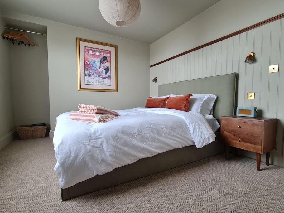 um quarto com uma cama grande com lençóis brancos e almofadas laranja em Trinity Square Loft + sea views em Kent
