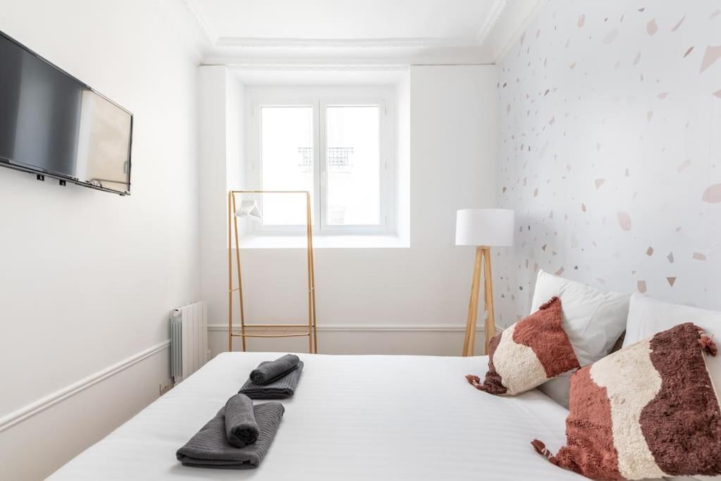 une chambre blanche avec un lit avec des serviettes dessus dans l'établissement Appartement agréable et cosy - III, à Paris