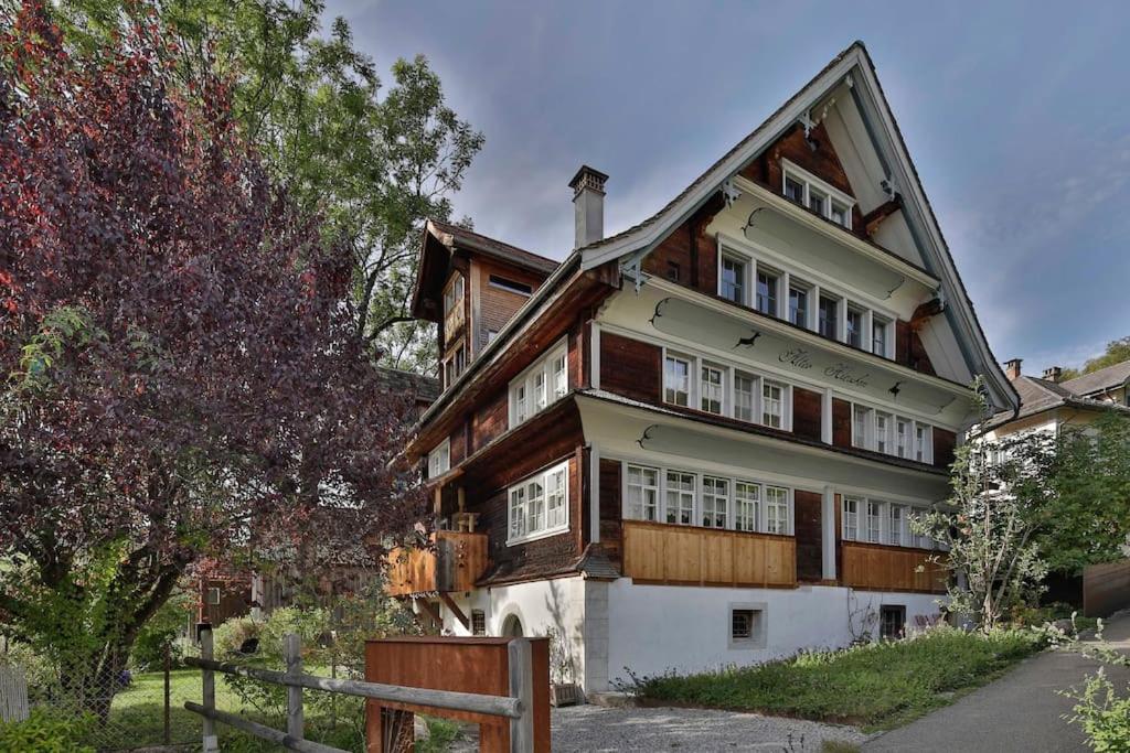 una gran casa de madera con una valla delante de ella en Ferien im Baudenkmal Toggenburg en Krummenau