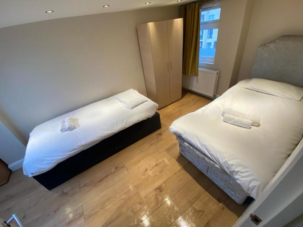 une chambre avec deux lits et une fenêtre dans l'établissement 4 Bedroom Apartment & 2 Bedroom apartment, à Londres