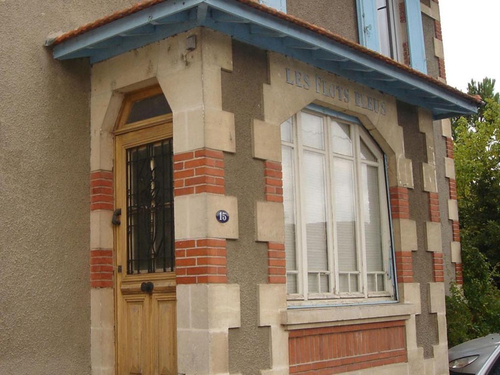 una casa con una porta in legno e una finestra di Les Flots Bleus a Andernos-les-Bains