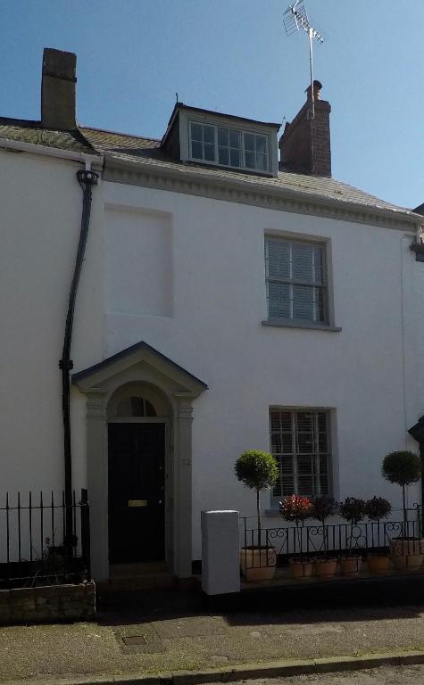 a white house with a door and a window at Laurel Cottage in Exmouth