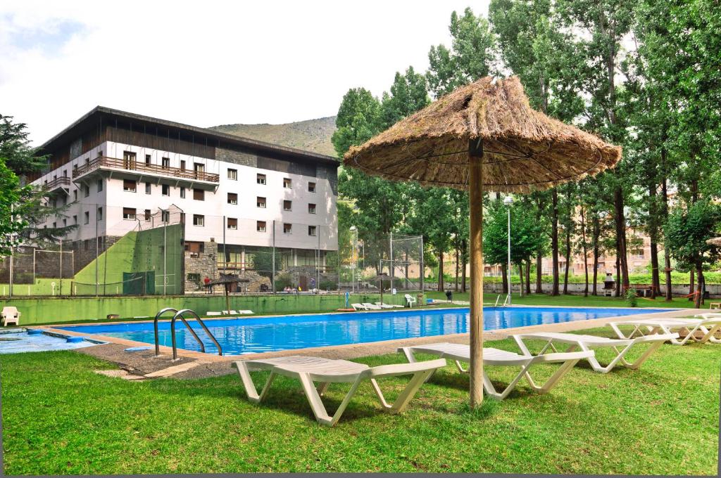 een zwembad met twee stoelen en een parasol ernaast bij RVHotels Condes del Pallars in Rialp