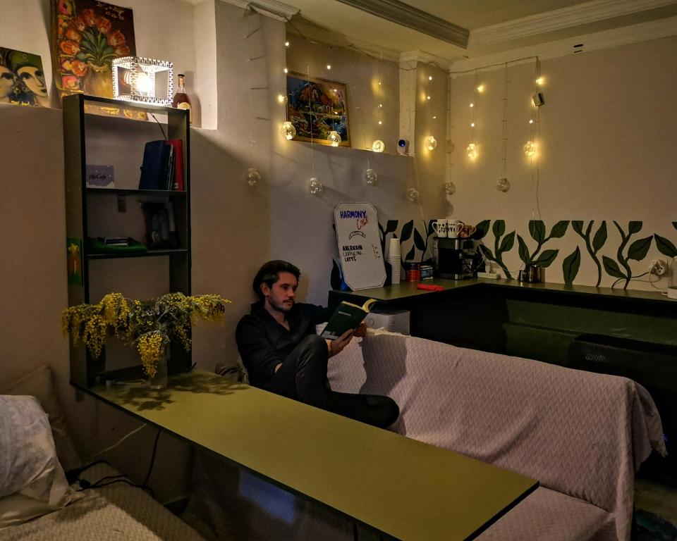 Un uomo seduto su un tavolo che legge un libro di Harmony Boutique Hostel a Batumi