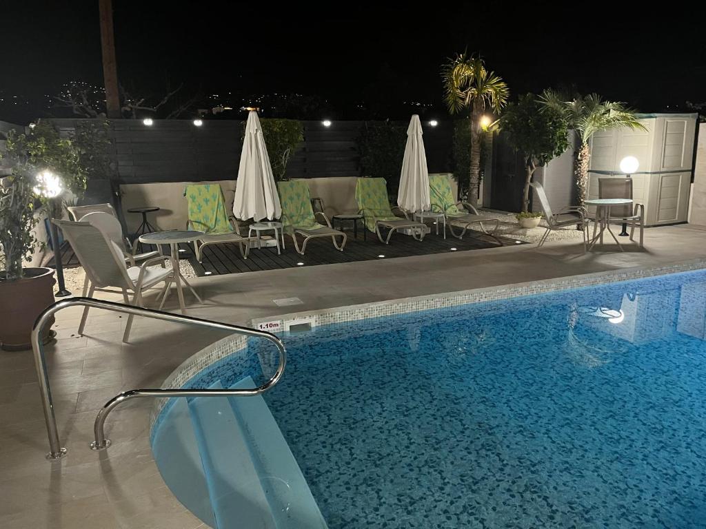 uma piscina à noite com cadeiras e guarda-sóis em 3 bedrooms villa with sea view private pool and enclosed garden at Kissonerga 4 km away from the beach em Kissonerga