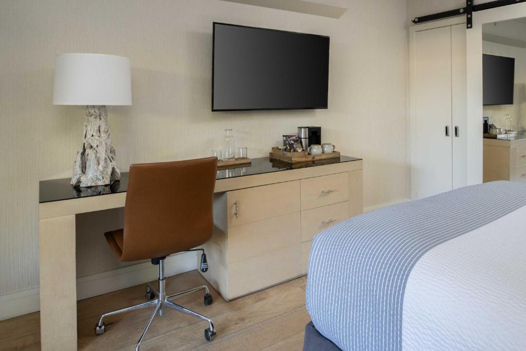 a bedroom with a desk with a television and a chair at Hotel Paradox, Autograph Collection in Santa Cruz