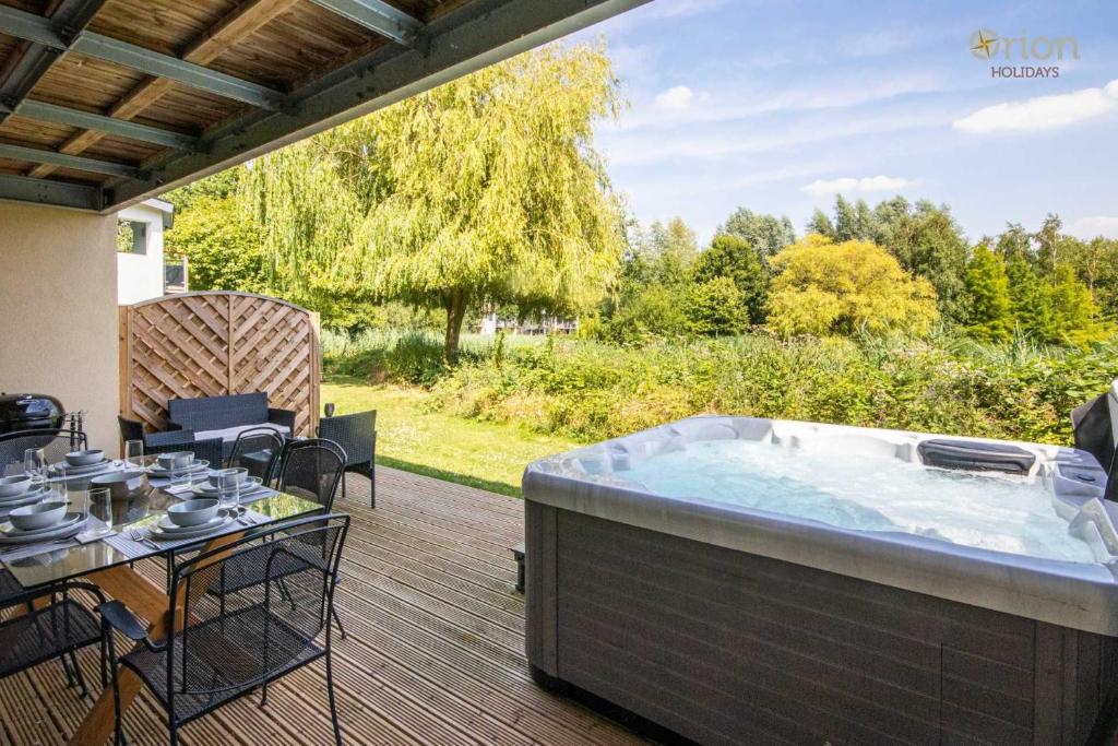 a hot tub on a deck with a table and chairs at Clearwater 74, Goldcrest P in Somerford Keynes