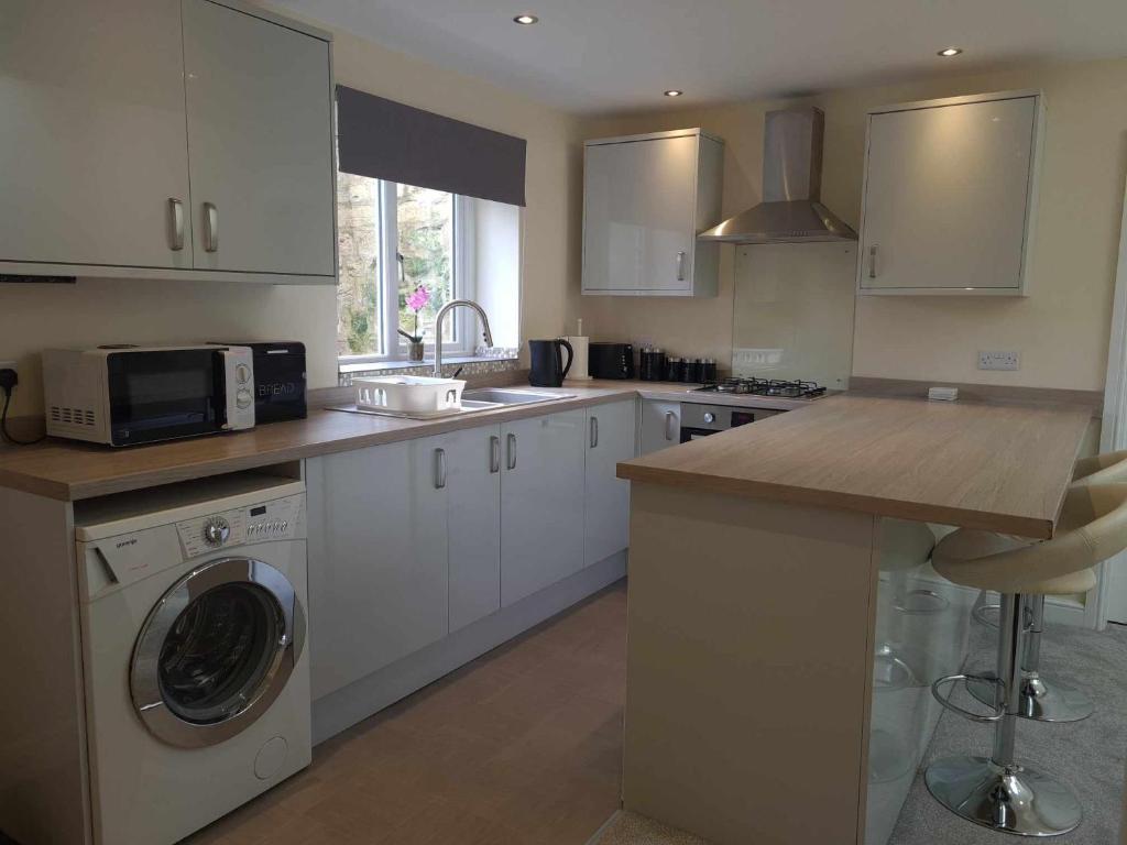 een keuken met een wasmachine en een magnetron bij 'The Potting Shed' in Knaresborough