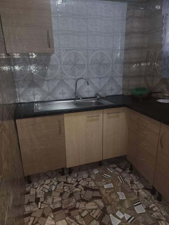 a kitchen with a sink and a tiled floor at Malikia Apartment 1 in Brusubi