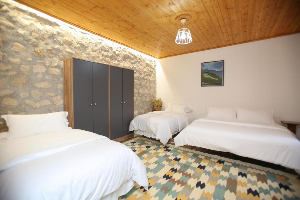 drie bedden in een kamer met witte lakens bij Guest House Bashaj in Bashaj