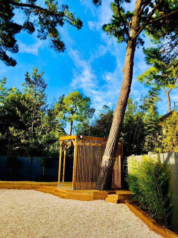 une clôture en bois avec un arbre à côté dans l'établissement Ondines, à La Baule