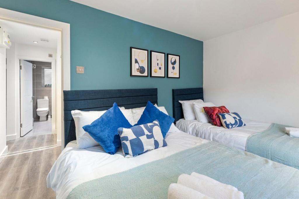 2 camas en una habitación con paredes azules en Diamond Suite Camden Town 3 Bedroom Sleeps 11 en Londres