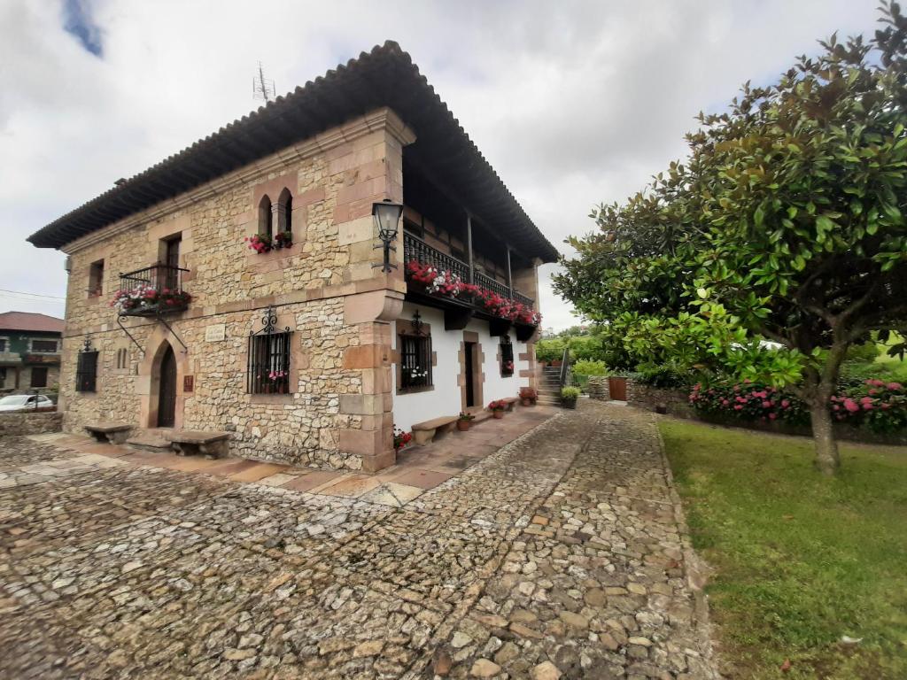 a stone house with flowers on a cobblestone street at La Casa Solariega in Santillana del Mar