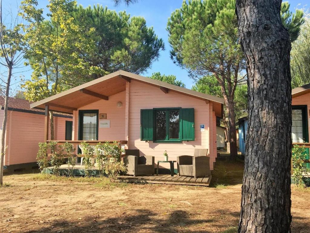 a pink house with a window and a tree at Holzchalet mit überdachter Veranda und Terrassenmöbeln auf einem schönen Campingplatz in Viareggio
