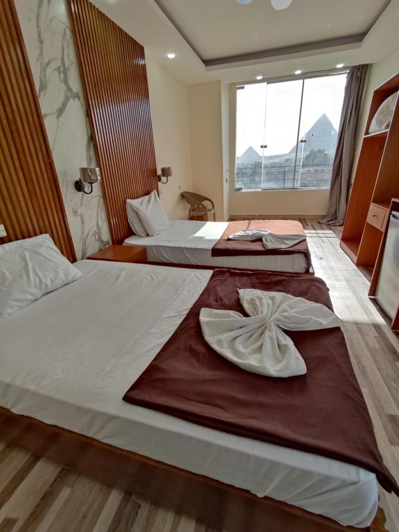 Dos camas en una habitación de hotel con toallas. en dream pyramids view, en El Cairo