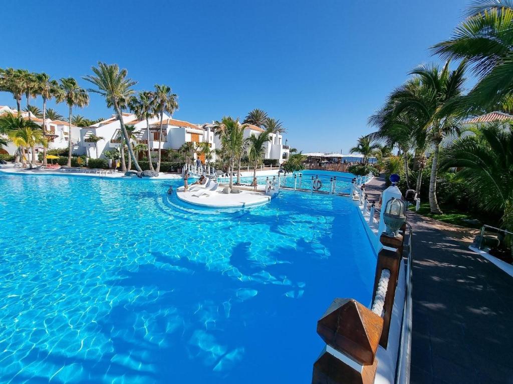 uma grande piscina com água azul e palmeiras em Schöne Wohnung in Playa De La Américas mit Gepflegtem Garten em Playa de las Americas