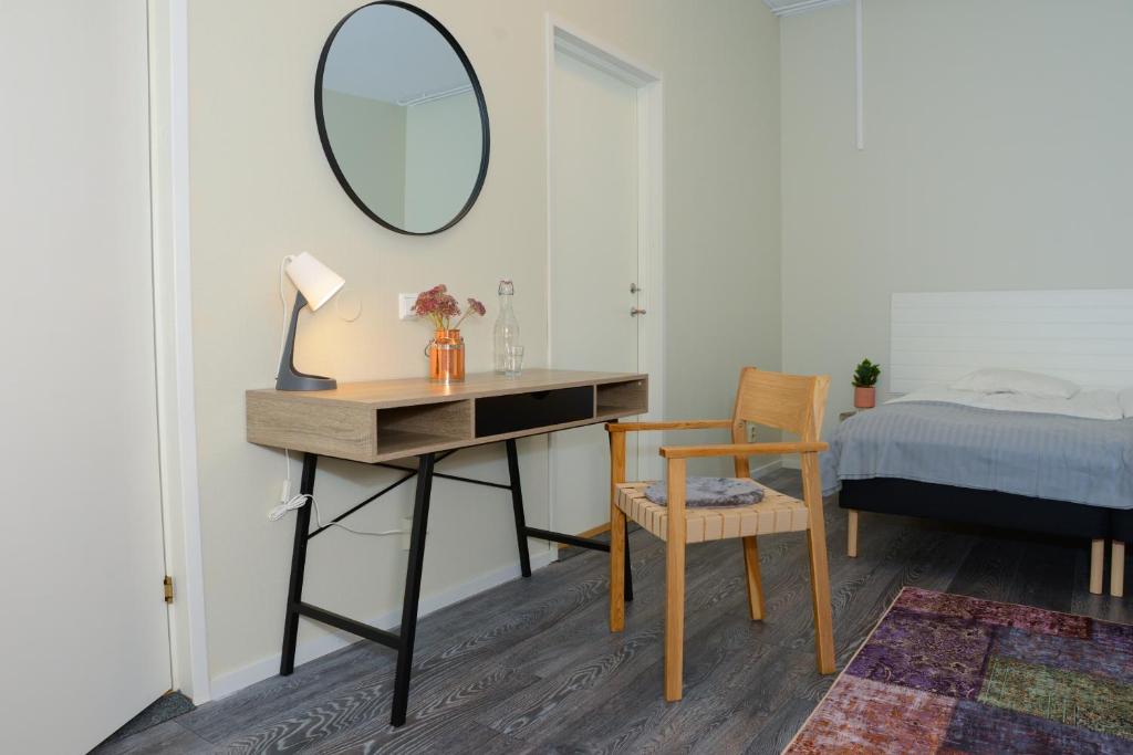 Schlafzimmer mit einem Schreibtisch, einem Spiegel und einem Bett in der Unterkunft Britz Hostel in Kristinehamn
